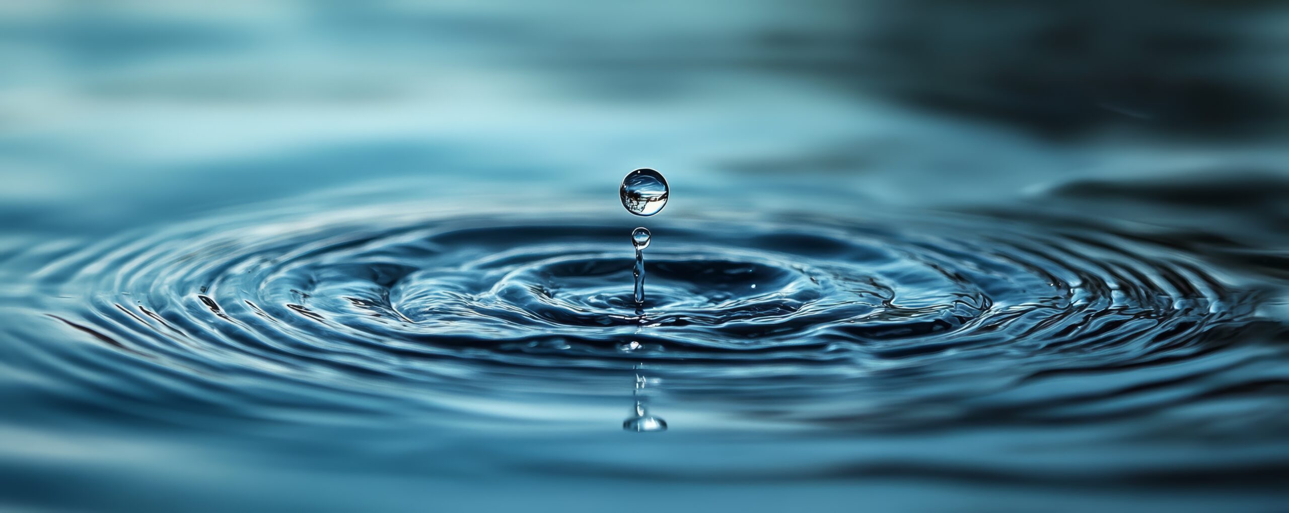 Macro shot of a single water droplet creating ripples on a calm water surface showcasing the beauty and simplicity of nature - SelectDr
